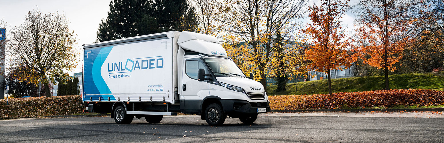 Dodávka firmy Unloaded na podzimní silnici.